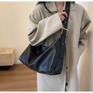 Détail du sac hobo noir grainé avec bandoulière large et boucle en métal doré texturé chic