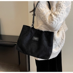Detail of black tote bag with embossed heart pattern on textured leather surface