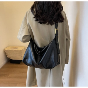 Détail du sac Hobo en cuir noir texturé avec boucle dorée sur la bandoulière large