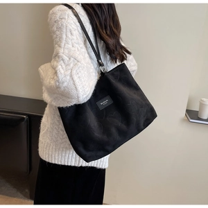 Close-up of black tote bag featuring textured 3D heart embossing and stylish logo patch