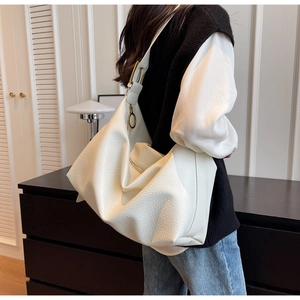Détail de la texture cuir blanc grainé et des boucles dorées sur le grand sac à main