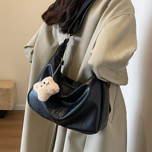 Black large capacity hobo shoulder bag with a plush bear charm on a female model