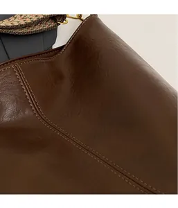 Close-up of brown vintage leather texture and bohemian woven strap with gold metal hardware