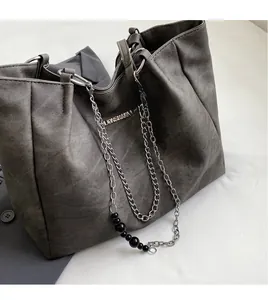 Close-up of charcoal gray tote bag showing matte texture and silver chain with black beads