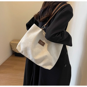 Close-up of heart jacquard texture on beige tote bag with brown leather brand tag