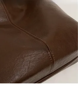Detail of dark brown leather texture with precise double stitching on a bucket bag