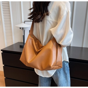 Détail du sac hobo en cuir marron avec anneau métallique sur la large bandoulière