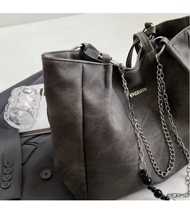 Detail of soft matte dark gray tote bag featuring decorative silver chain and beads