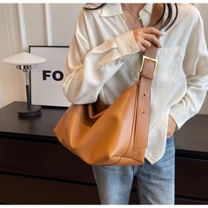 Détail du sac en cuir caramel montrant le grain de litchi et la boucle dorée