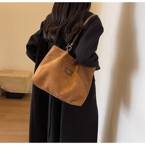 Close-up of heart embossed texture on caramel brown suede tote bag with shoulder strap