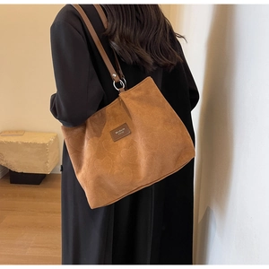 Close-up of caramel tote bag featuring embossed heart patterns and leather logo patch