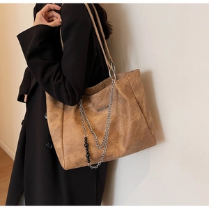 Close-up of brown vintage leather tote bag with unique metal and bead chain decoration