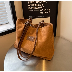 Detail of a brown tote bag featuring embossed heart patterns and durable leather handles