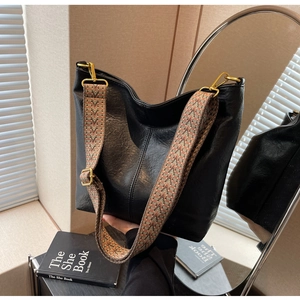 Detail of black large capacity bucket bag with colorful bohemian wide shoulder strap