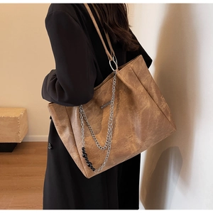 Detail of vintage brown tote bag with matte texture and decorative silver chain strap