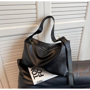 Détail du sac hobo en cuir grainé noir avec bandoulière large et anneaux dorés