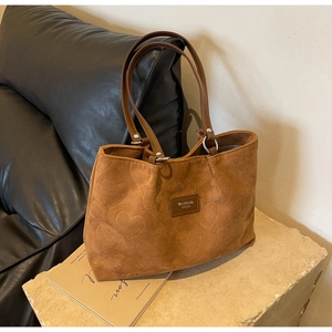 Detail of brown corduroy tote bag featuring embossed heart patterns and leather strap