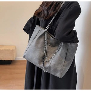 Detail of grey tote bag with vintage texture and stylish silver chain shoulder strap