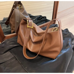 Détail du sac en cuir marron grainé avec boucle dorée vintage et bandoulière large