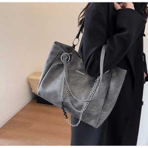 Detail view of large grey tote bag featuring layered silver chains and a matte texture