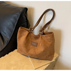 Detail of brown faux suede tote bag with heart embossing and leather handles