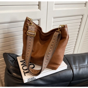 Close-up of caramel brown tote bag with retro ethnic pattern woven wide shoulder strap