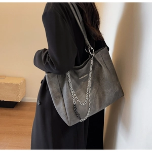 Detail of grey large tote bag showing textured leather, silver chains, and metal logo