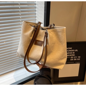 Close-up of heart jacquard texture and brown leather label on cream canvas tote bag