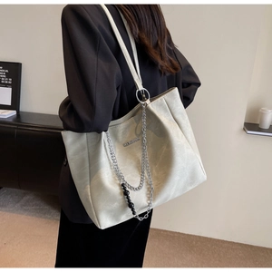 Detail of light grey leather tote bag featuring stylish silver chain and black bead charm