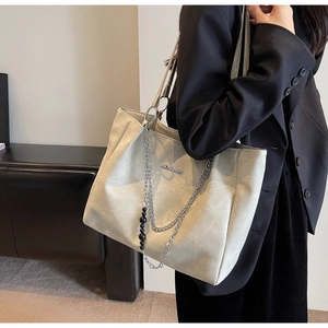 Detail view of large grey tote bag with silver chain strap and beaded decor on model