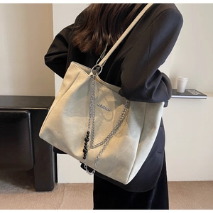 Close-up of beige tote bag showing matte texture and stylish silver chain detail