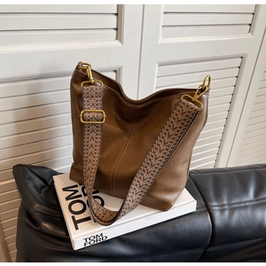 Close-up of brown pebbled leather hobo bag with vintage gold hardware and woven strap
