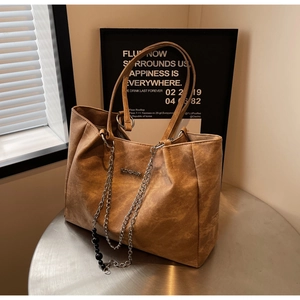 Close-up of vintage brown tote bag texture with metal logo and stylish chain detail