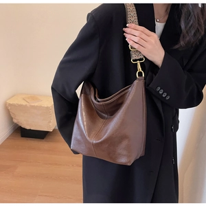 Detail of a large brown vintage tote with floral woven strap and golden hardware buckle