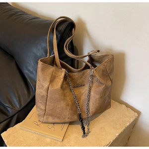 Detail of vintage brown tote bag with silver chain decor and textured synthetic leather