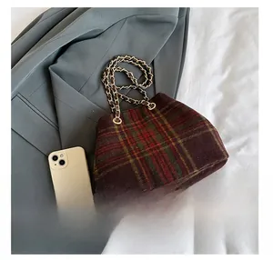 Detail presentation of vintage plaid bucket bag size compared to a white smartphone