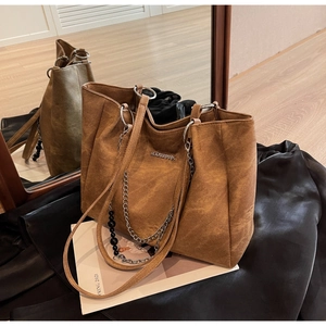 Detail view of large brown faux leather tote bag with metal chain and bead strap detail