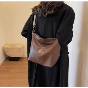 Detail of a brown leather Hobo bag with a geometric pattern wide shoulder strap
