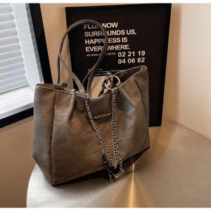 Detailed macro view of large grey tote bag featuring metal chain and beaded charms