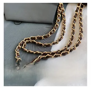 Detail of vintage gold metal chain strap woven with dark brown leather on a bag