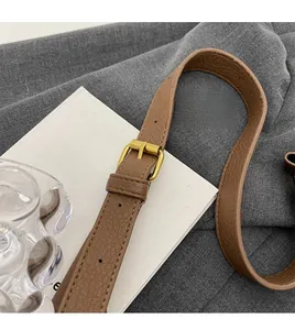 Close-up of brown pebbled leather adjustable shoulder strap with gold-tone metal buckle