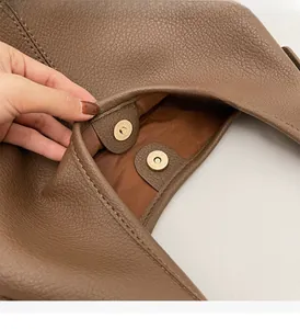 Detail of premium brown pebble leather bucket bag with magnetic golden metal buckle