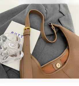 Detail of brown pebble leather tote featuring magnetic buckle and adjustable strap