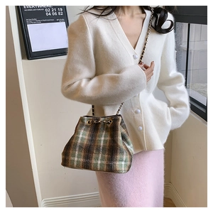 Detail of tweed bucket bag with brown green plaid pattern and gold chain strap