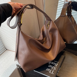 Sac hobo en cuir marron avec texture litchi et bandoulière large reflété dans un miroir