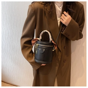 Détail d'un sac seau noir avec foulard en soie et blazer marron pour un look élégant
