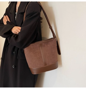 Close-up of brown suede and leather bucket bag showing material texture and shoulder strap