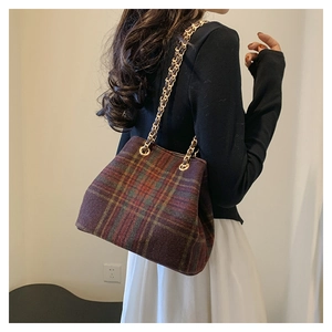 Detail of vintage plaid wool shoulder bag with golden chain strap on a model