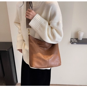 Detail of brown leather tote with vintage wide patterned strap and bronze metal hardware