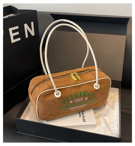Gros plan d'un sac cylindre en daim marron avec poignées blanches dans un coffret cadeau